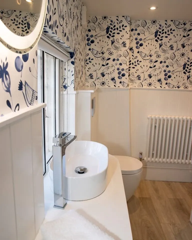 Folk bird wallpaper trimmed around a vanity, blind and window frame