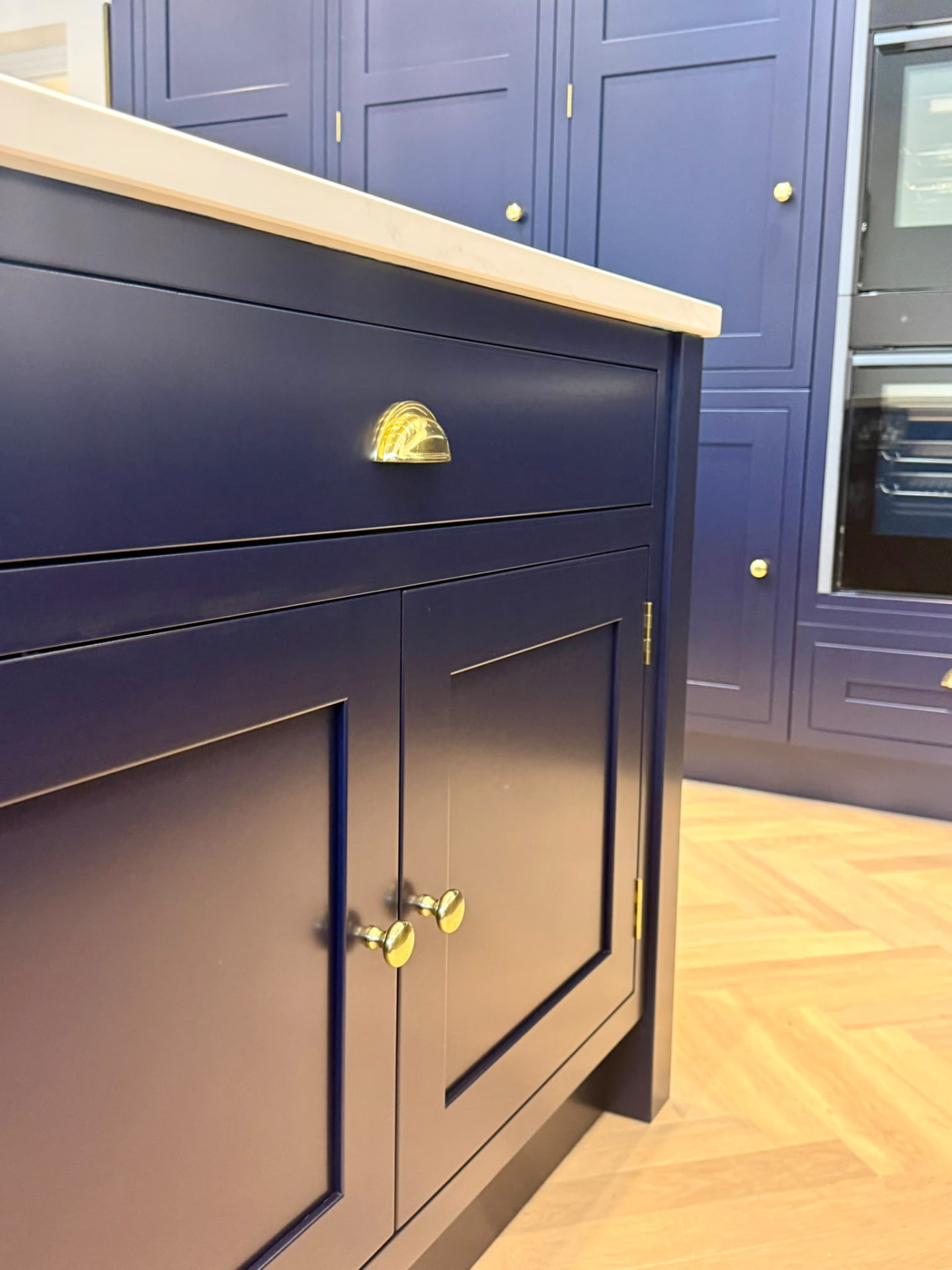 Close view of navy hand painted kitchen island doors, drawer front and polished brass hardware