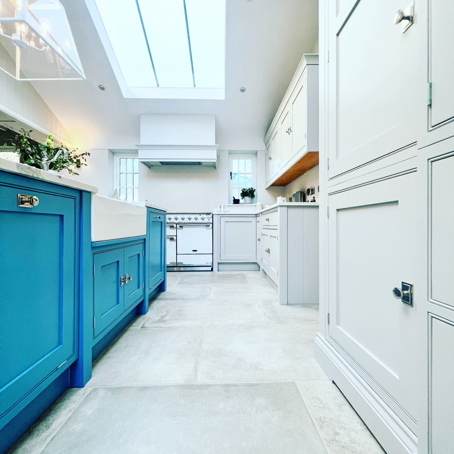 Low-level view of blue and pale grey hand painted kitchen cabinetry beneath a roof light