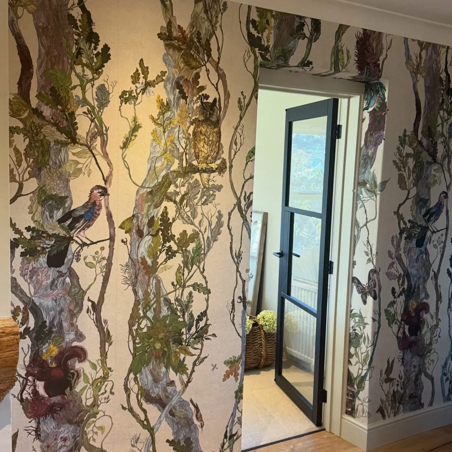 Woodland wallpaper hung around a doorway with the pattern continuing over the reveal