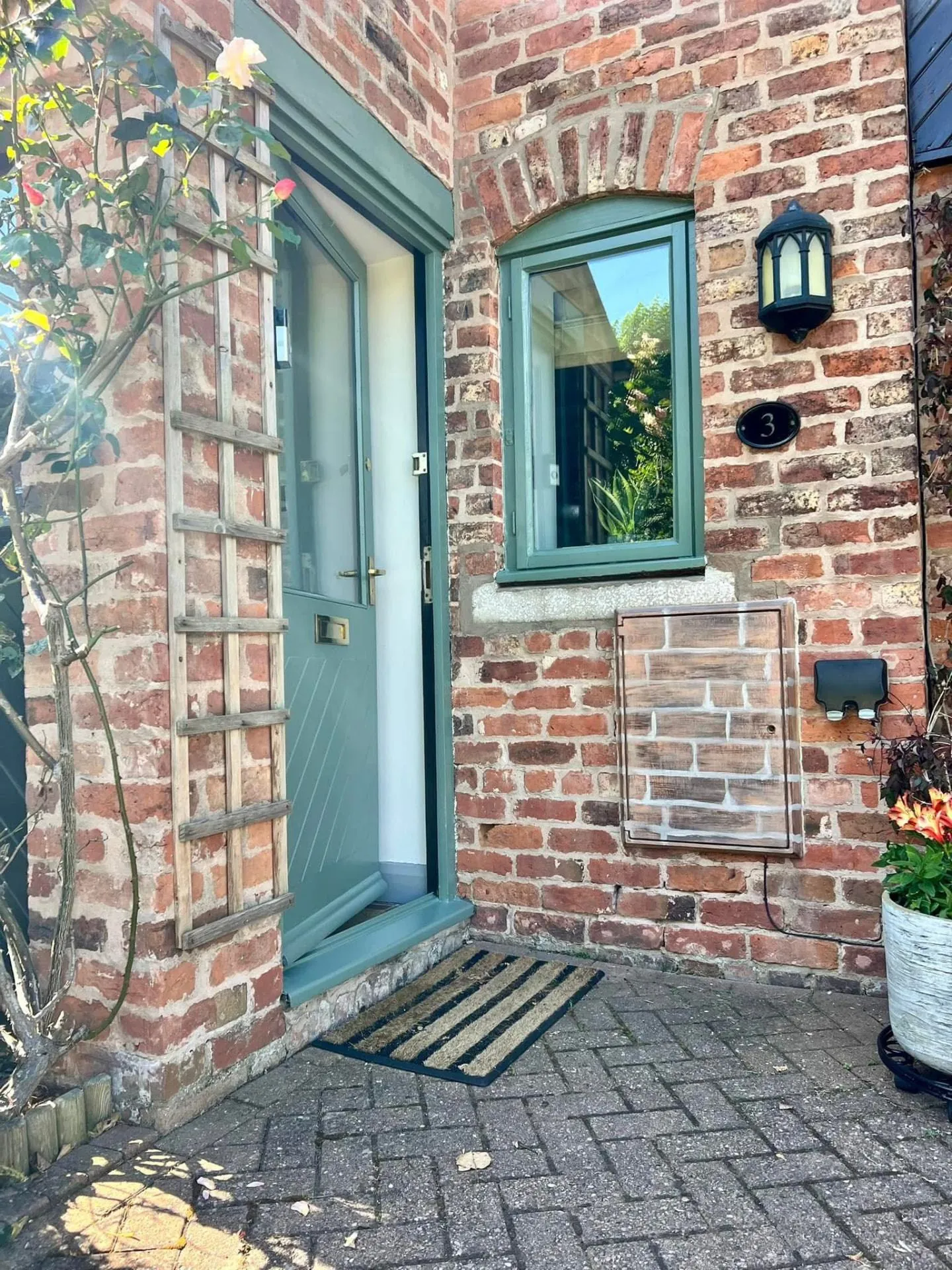 Repainted front door and window frame in a soft green finish