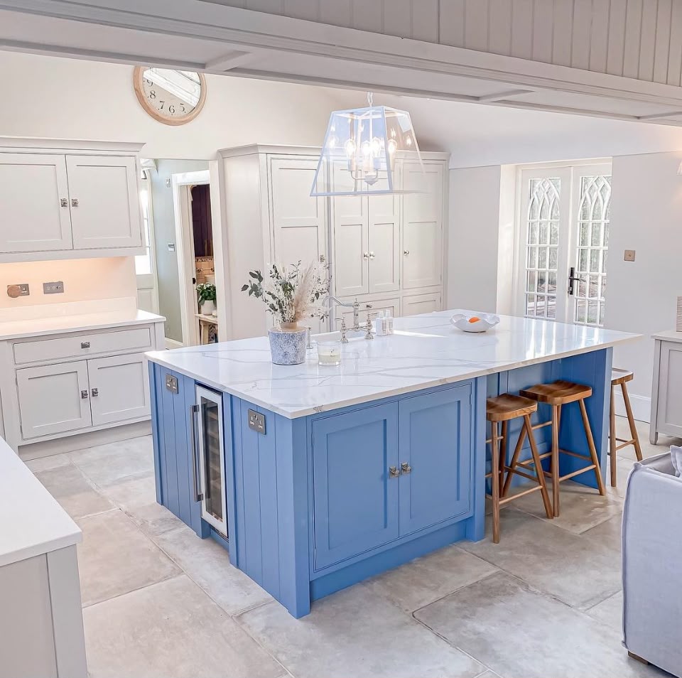 Hand painted blue kitchen island with pale grey cabinetry, quartz worktops and timber stools