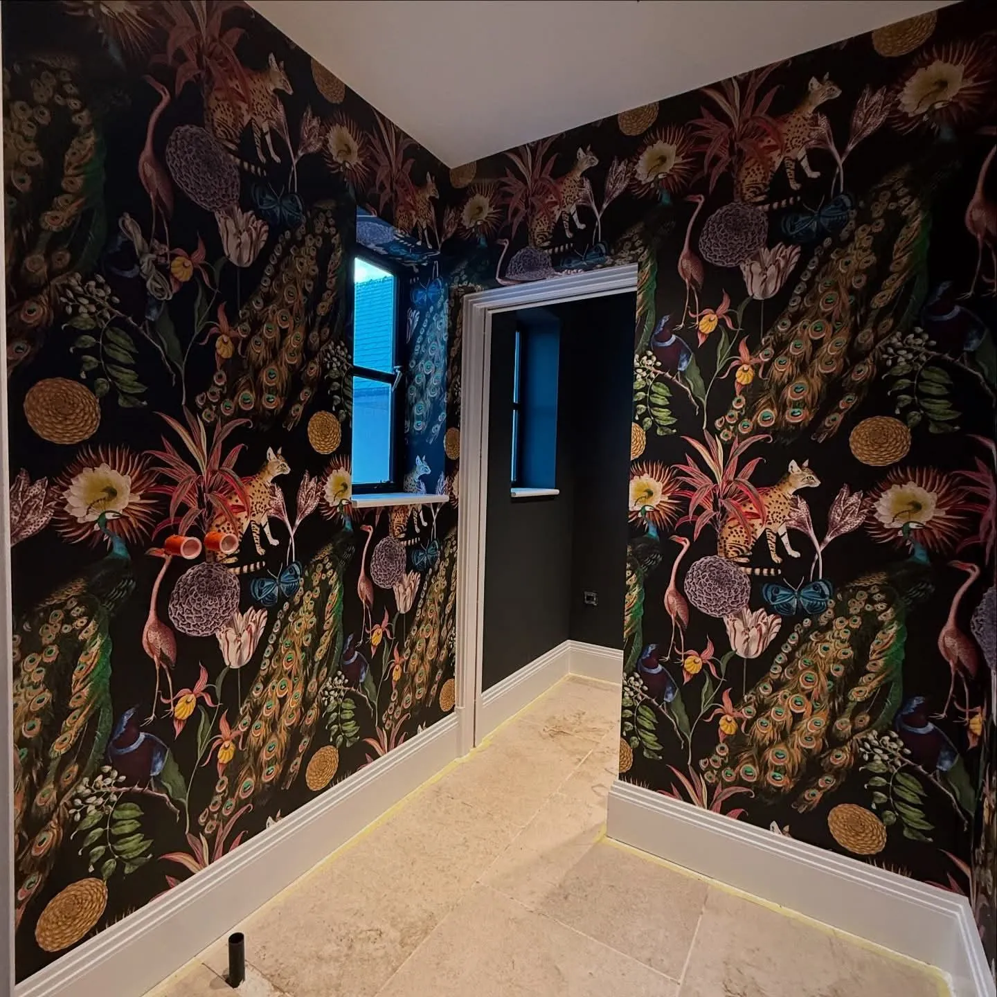 Tropical dark wallpaper carried across four walls and a window reveal