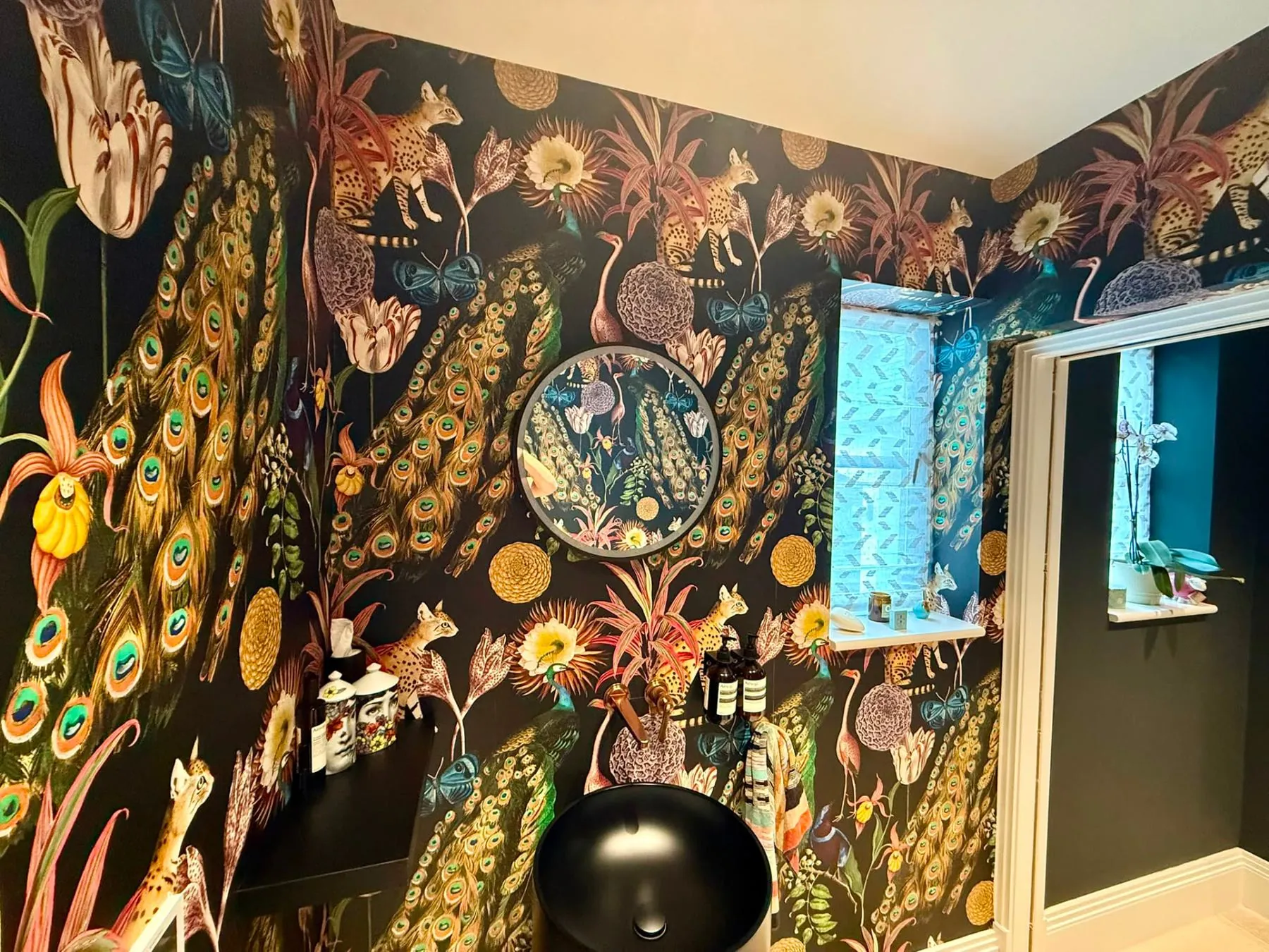 Dark botanical peacock wallpaper hung around a cloakroom with matched corners