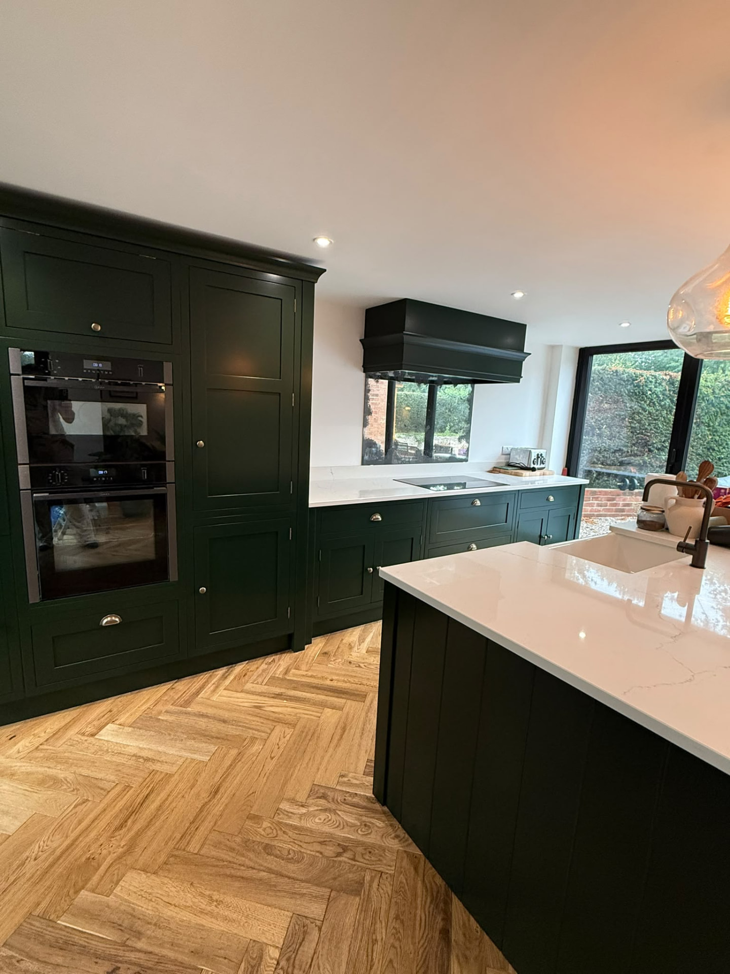 Bespoke dark green hand painted kitchen cabinetry with quartz worktops and brass hardware