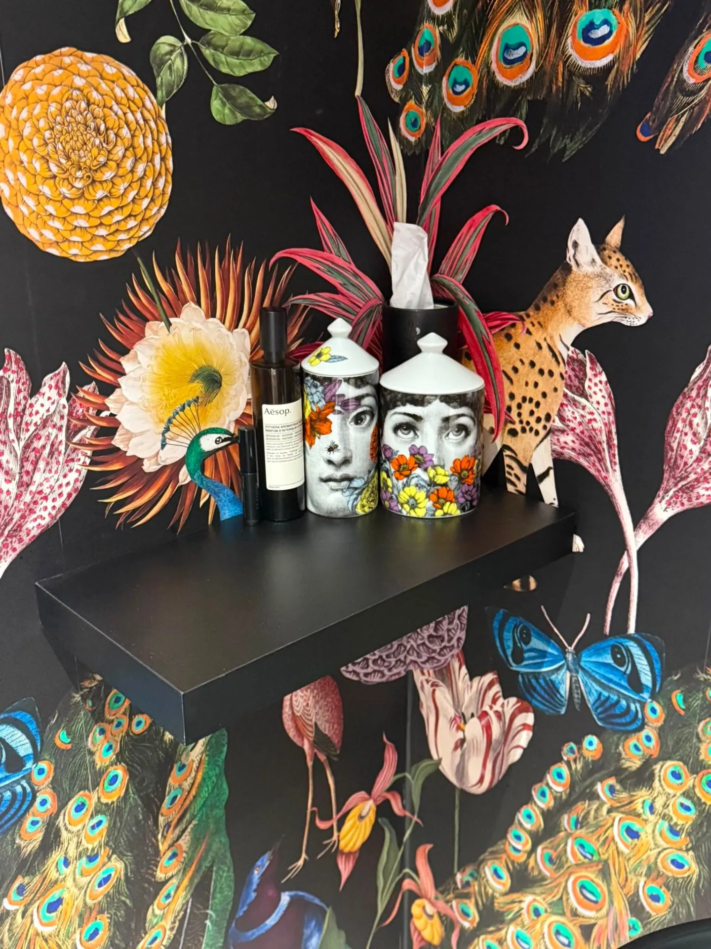 Close detail of peacock and botanical wallpaper seams behind a floating shelf