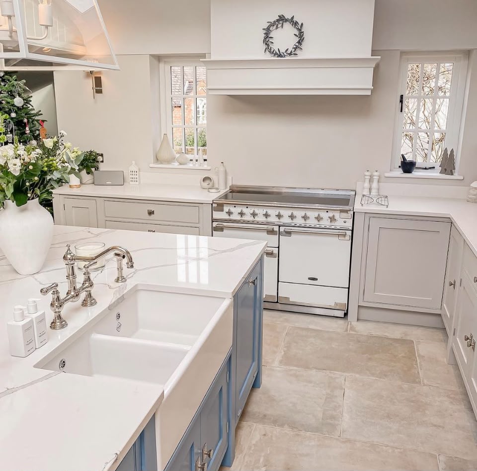 Blue hand painted kitchen island with Belfast sink facing a pale grey range cooker wall