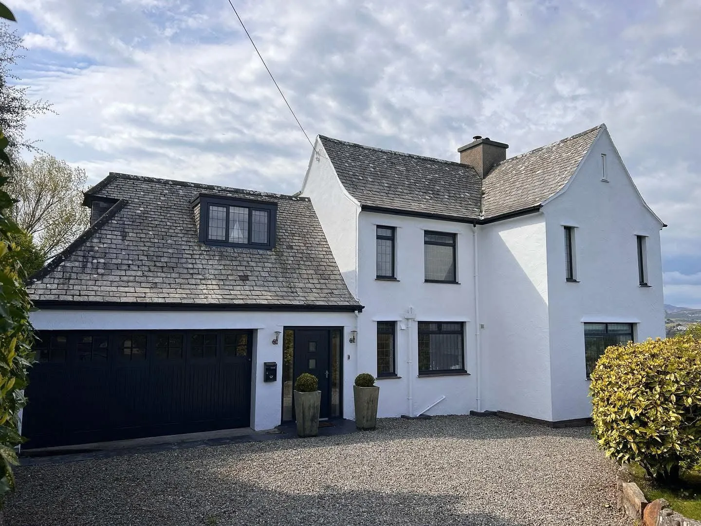 White rendered house with dark garage doors and trim after exterior repaint