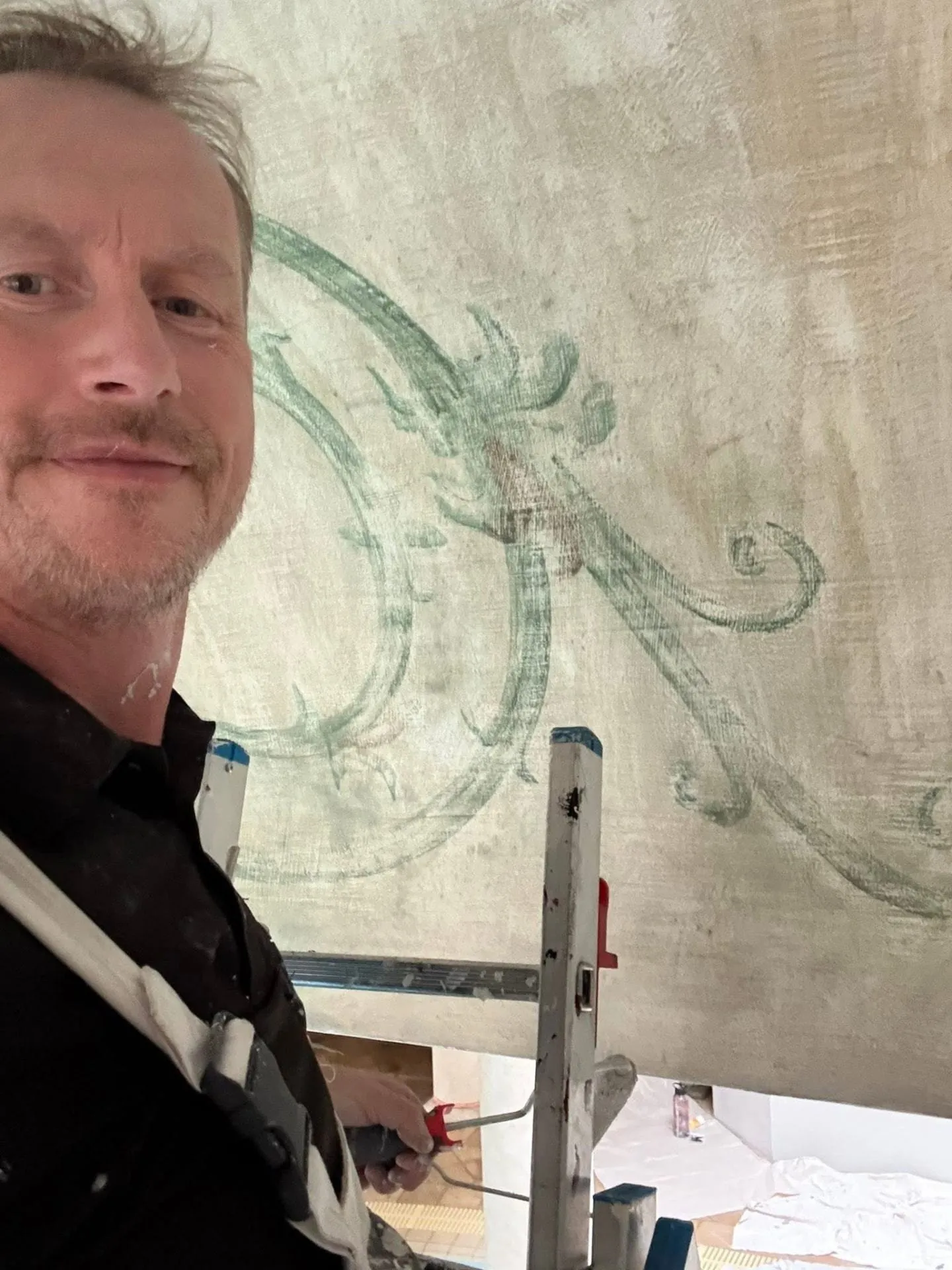 Adam Day, painter and decorator, on site beside a large decorative wall mural mid-glaze