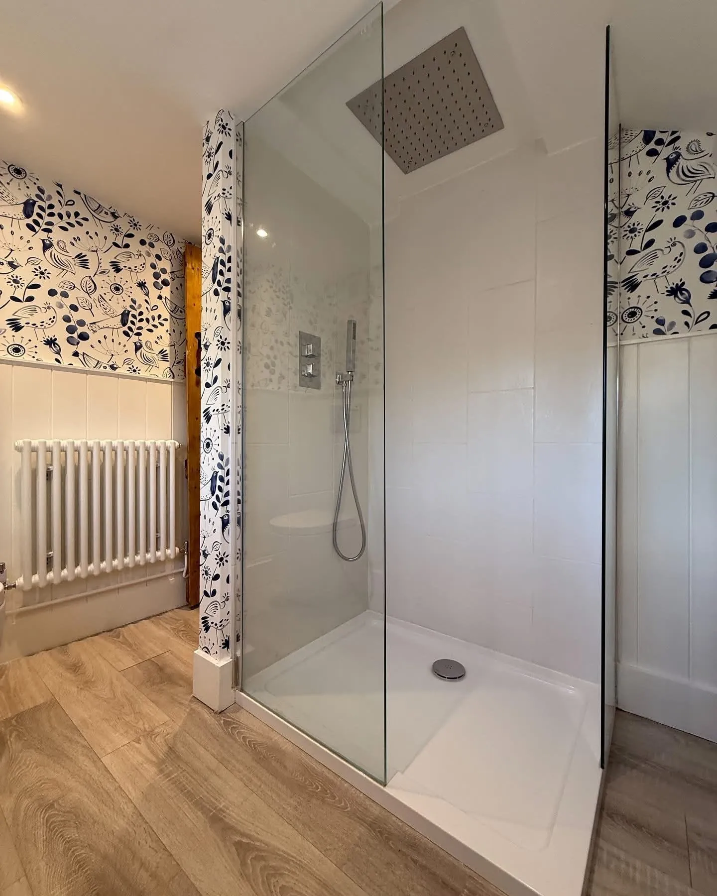 Folk bird wallpaper hung on narrow returns beside a walk-in shower