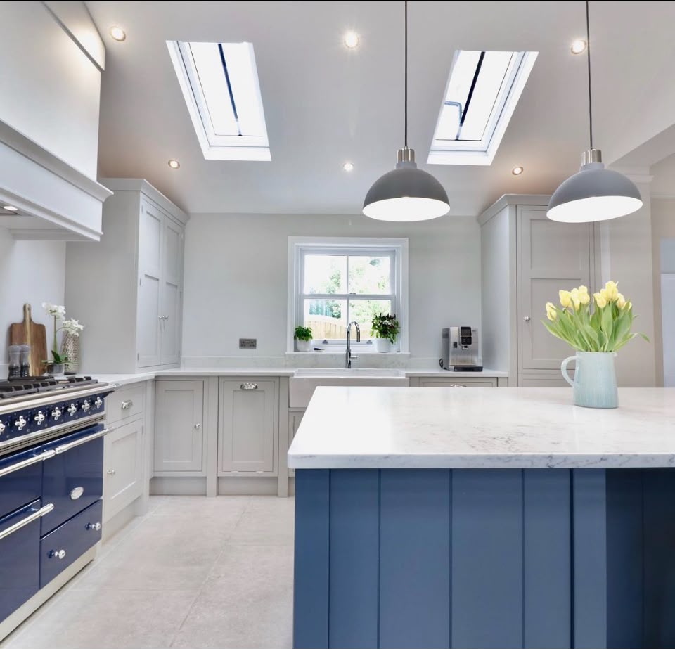 Blue hand painted kitchen island with pale grey cabinets, blue range cooker and roof lights