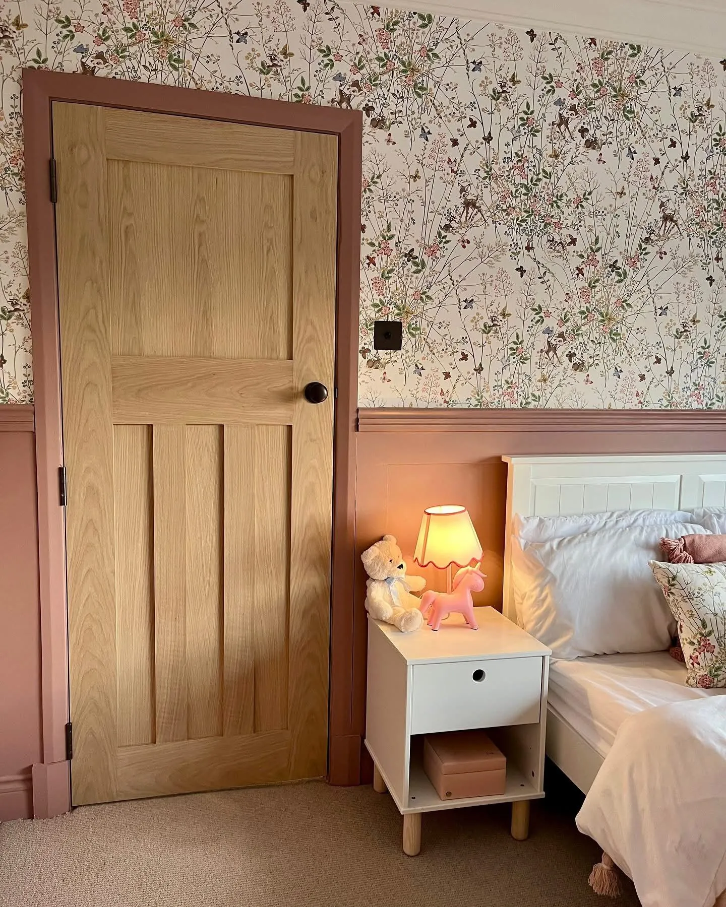 Carefully finished dusty pink interior panelling beneath meadow wallpaper