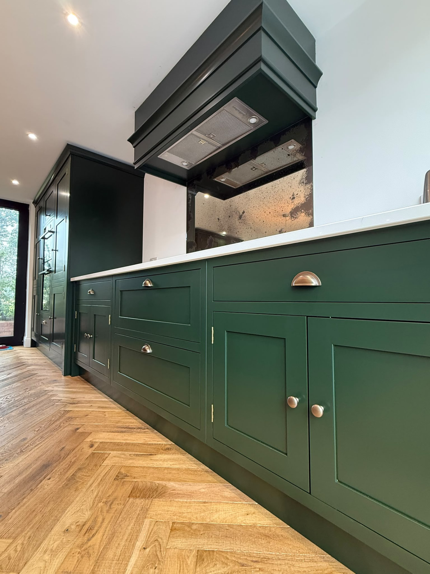 Dark green bespoke hand painted kitchen cabinets with brass cup handles and a smooth eggshell finish